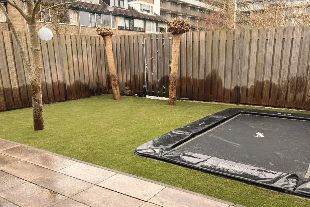 Na: met strak kunstgras rond de ingegraven trampoline