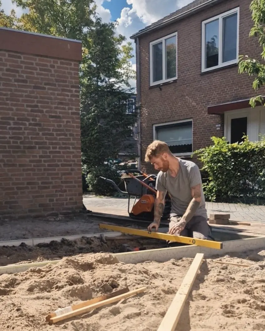 Rob legt met een waterpas de opsluitbanden van een nieuwe voortuin recht